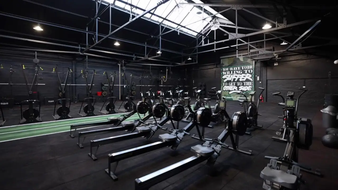 The main floor at Commando X-Fit: rowers, air bikes, ski machines and the turf track under the roof lights