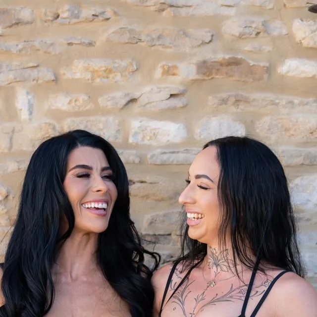 Two team members laughing against a stone wall at the June shoot