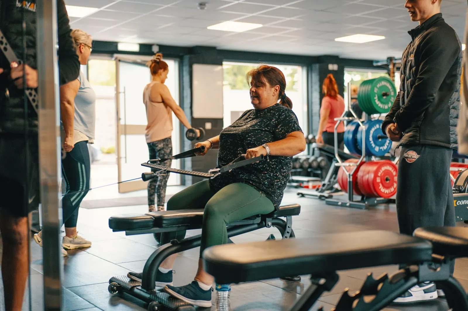 A member on the cable row during a small group session at Level Up Fitness, with others training behind her