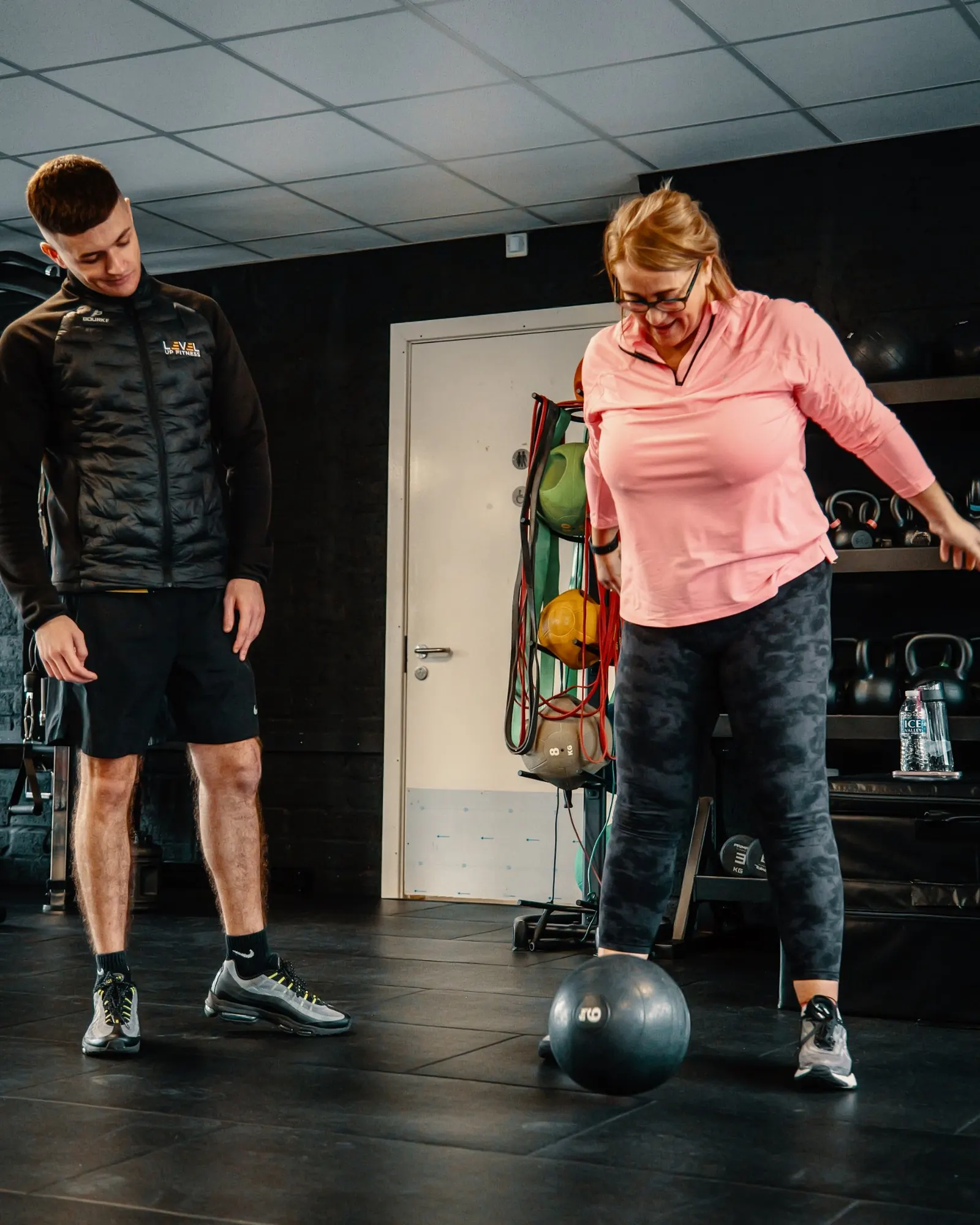 A coach watching a member work with a medicine ball at Level Up Fitness