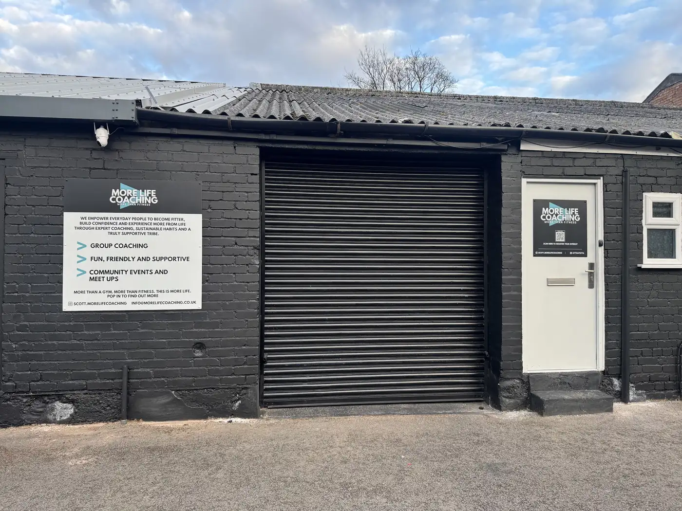 The outside of the More Life Coaching unit on Reddicap Trading Estate: black brick, a roller shutter and the More Life Coaching sign
