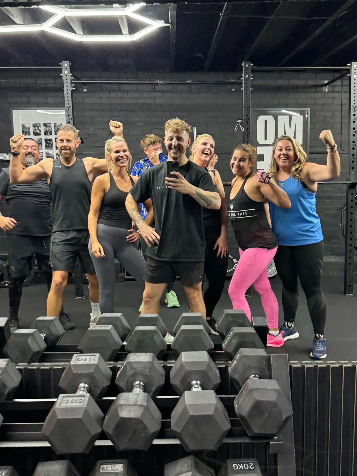 A small group of More Life Coaching members posing behind the dumbbell rack after a session