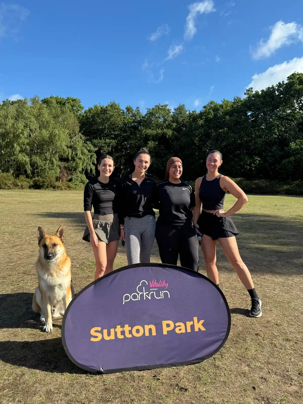 More Life Coaching members and a dog behind the Sutton Park parkrun banner