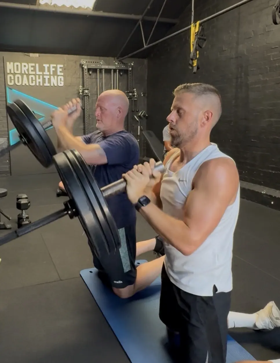 Two members doing a landmine press side by side at More Life Coaching