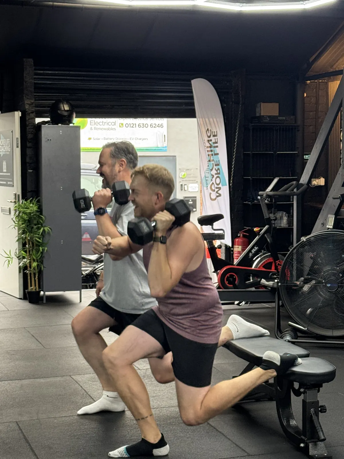 Two members doing dumbbell split squats on benches at More Life Coaching